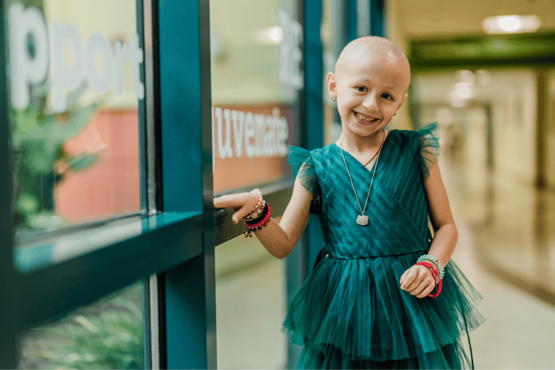 A little girl smiles as she poses in a hallway
